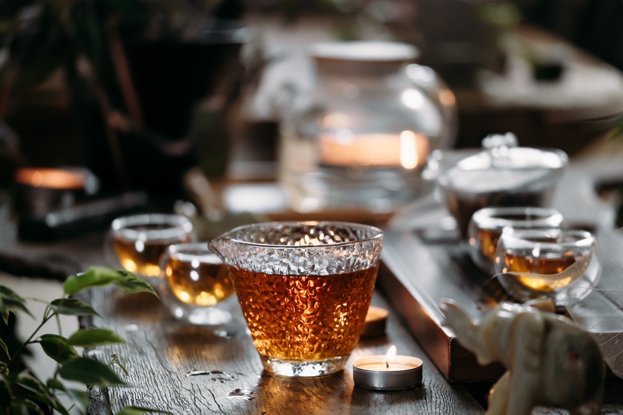 An elegant tea setup with glass teaware and warm candlelight, creating a cozy and inviting ambiance.